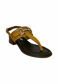 Sandalia de cuero marrón con diseño de tira entre los dedos, correa ajustable en el tobillo, acentos circulares plateados y un tacón bajo apilado.