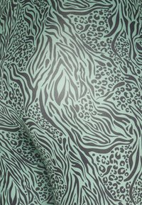 Kuvioitu kangas, jossa on piparmintunvihreä tausta ja musta eläinkuosissa aaltoilevia viivoja, mukaan lukien seepra- ja leopardikuvioita. Pehmeä, teksturoitu pinta.