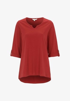 Red, soft fabric top with a V-neck, three-quarter sleeves, and rolled cuffs. Curved hemline, designed for comfort and ease of movement.