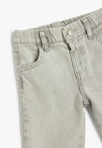 Lysegrå denimbukser med ribbet talje, bæltestropper, frontlommer og subtil strukturmærkning i stoffet.