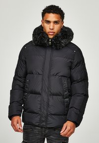 Jachetă puffer neagră cu guler din blană sintetică, design matlasat, detaliu imprimat "GLORIOUS" pe partea din față și buzunare cu fermoar.