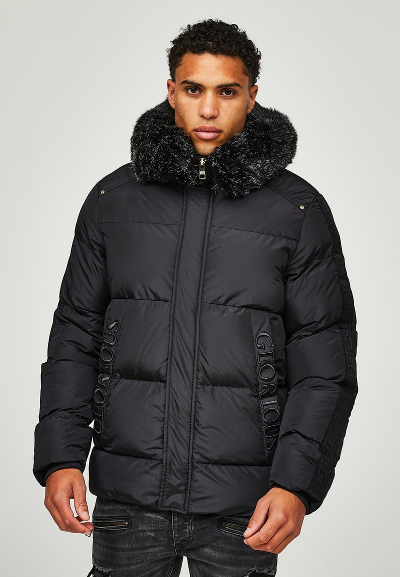 Jachetă puffer neagră cu guler din blană sintetică, design matlasat, detaliu imprimat "GLORIOUS" pe partea din față și buzunare cu fermoar.