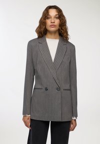 Szary żakiet w paski z podwójnym zapięciem, klapami połówkowymi, dwiema przednimi kieszeniami oraz czarnymi guzikami. Gładka faktura i dopasowany krój.