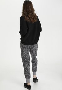 Sort, fluffy sweater parret med grå leopardprint joggers. Joggers har ribbede manchetter og er stylet med sorte platform sneakers.