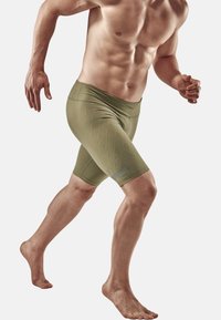 Enganliegende, olivgrüne Sportshorts mit strukturiertem Rautenmuster und elastischem Bund, entworfen für Bewegungsfreiheit und Komfort.