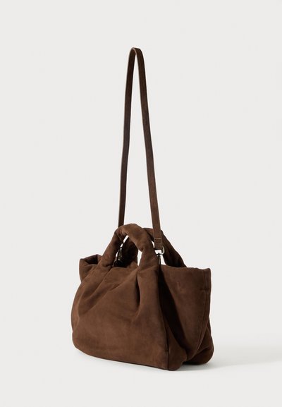 Pruun seemisnahast käekott, millel on tekstureeritud pind, pehme struktuur, kaks ülaosa käepidet ja pikk õlavarre rihm. Omab lihtsat ja funktsionaalset disaini.