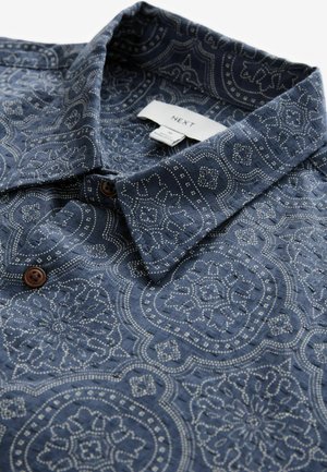 Navy blue patterned shirt with intricate white designs, featuring a classic collar and brown buttons, made of a textured fabric.