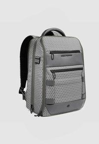 Zaino grigio con motivi geometrici, due scomparti con cerniera, schienale imbottito e cinghie aggiuntive per un trasporto sicuro. Accenti con texture liscia.