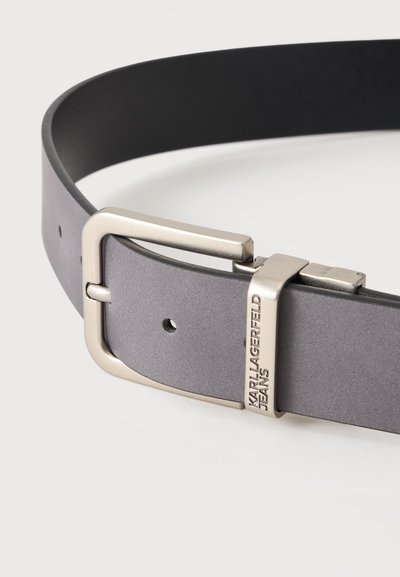 Ceinture en cuir gris avec une boucle en métal argenté et une boucle gravée du texte ""KARL LAGERFELD JEANS"" sur fond blanc.