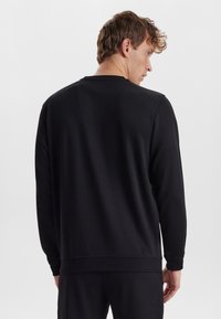 Sort sweatshirt med rund hals og lange ærmer, med ribbede manchetter og kant, glat tekstur og en afslappet pasform.