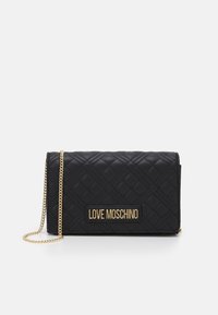 Borsa a tracolla nera trapuntata con una catena d'oro e una vistosa placca con logo dorato. Texture liscia con dettagli a motivo diamante.