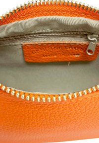 Pochette in pelle arancione con texture, dotata di una cerniera argentata e rivestimento in tessuto, che rivela un piccolo scomparto interno per lo stoccaggio.