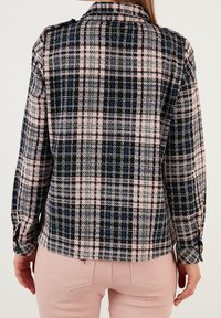 Camicia a quadri nei colori nero, rosa e blu; presenta un collo, maniche lunghe e dettagli con bottoni; tessuto testurizzato con una vestibilità strutturata.