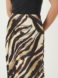 Une jupe fluide avec un motif abstrait de rayures de tigre crème et marron ; fabriquée en tissu léger avec une texture douce et une taille ajustée.