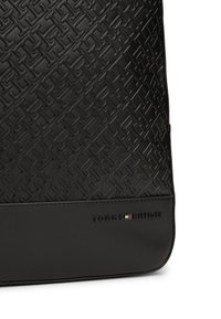 Borsa in pelle nera embosso con un motivo geometrico, texture liscia e un logo marchiato in un colore contrastante sul fondo.