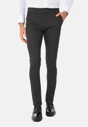Pantaloni neri con un motivo testurizzato, vestibilità slim, cinque tasche e chiusura con bottone. Abbinati a scarpe nere lucide.