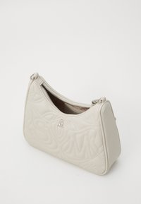 Beige quiltet lædertaske med lynlås, med en glat overflade og præget mønster. Pyntet med sølvhardware.