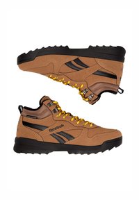 Hnedé semišové turistické topánky s čiernymi doplnkami, žltými šnúrkami a čiernou gumovou podrážkou. Vyznačujú sa kovovým kovaním pre odolnosť a vodeodolnosť.
