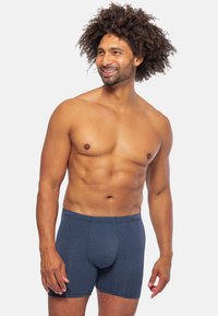 Boxer da uomo blu navy con un motivo geometrico testurizzato. Realizzati in tessuto elasticizzato, presentano una forma aderente e una vita elastica.