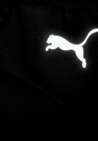 Zwarte stof met een wit springend poema-logo, gladde textuur, met contrasterende kleuren voor duidelijke zichtbaarheid en merkherkenning.