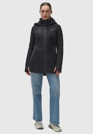 Black zip-up jacket with a textured fabric, hood, and two side pockets, paired with light blue jeans and grey sneakers.