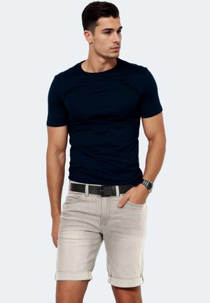 Navy blue fitted t-shirt made of cotton, paired with light grey denim shorts with rolled cuffs, and a black belt. Casual style.