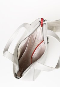 Borsa a tracolla in pelle bianca con chiusura a zip, accentuazione interna rossa e foderatura a fantasia. Presenta due scomparti e manici resistenti.