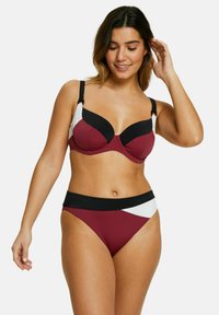 Maillot de bain deux pièces en bordeaux, noir et blanc. Le haut bralette présente des armatures, des bretelles réglables ; le bas a une taille haute avec un design en blocs de couleurs.