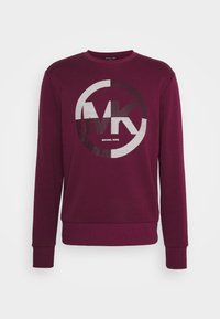 Sudadera color burdeos con un logo redondo que presenta "MK" en blanco y negro. Tejido suave, cuello redondo y puños y dobladillo acanalados.
