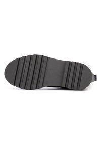 Suela de zapato de goma negra con ranuras horizontales, ligera textura y marca. Forma curvada y diseño plano para mayor estabilidad.