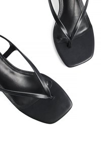 Zwarte platte sandalen met een vierkante teenontwerp, gemaakt van soepel leer, met dunne kruisende banden en een minimalistische esthetiek.