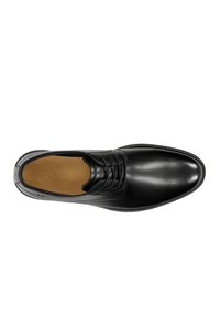 Scarpa da uomo nera in pelle lucida con finitura liscia, design con lacci e punta rotonda. La soletta è di colore cammello con il marchio, e presenta una suola texturizzata.