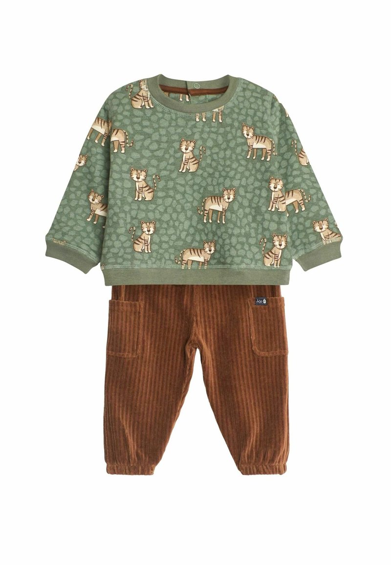 Grünes Langarmhemd mit einem Tigerprint auf einem strukturierten Hintergrund, kombiniert mit braunen Cordhosen mit Taschen und gerippter Textur.