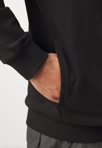 Sort crewneck sweatshirt med ribbede manchetter og en sidelomme. Glat tekstur med en tætsiddende design, velegnet til afslappet brug.