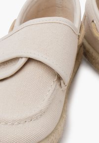 Scarpe in tela beige con punta arrotondata, design a strisce sovrapposte e suola in juta testurizzata per maggiore aderenza e durata.