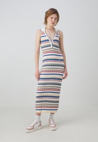 Vestido de punto sin mangas con un profundo escote en V, con rayas verticales en azul, verde, rojo y amarillo. Textura acanalada, de longitud media.