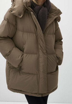Brown oversized puffer jacket with high collar and side pockets worn over a dark scarf and black pants.
