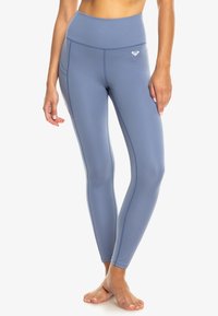 Leggings de sport bleu clair avec une taille haute, dotées de poches latérales et de coutures plates pour plus de confort. Fabriquées en tissu extensible et lisse.