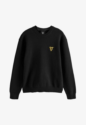 Hanorac negru cu decolteu rotund, mâneci lungi, manșete și tiv reiate. Are un mic logo cu o harpă galbenă brodată pe piept.