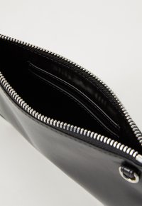 Must musta rahakott, millel on hõbedane lukk ja avar sisemus koos eraldi kaardipesadega. Tekstureeritud pind ja sujuv viimistlus.