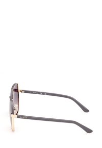 Sluneční brýle s šedým plastovým rámem, zlatými kovovými akcenty a gradientními tmavými skly. Mají rovné nožičky a nosní polštářky pro pohodlí.