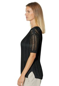 Schwarzer gestrickter Pullover mit kurzen Ärmeln, der ein strukturiertes Design, seitliche Schlitze und einen lockeren Schnitt bietet und aus einem atmungsaktiven Stoff für mehr Komfort gefertigt ist.
