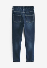 Jean en denim bleu foncé avec ceinture élastique et deux poches arrière, présenté à plat de dos sur un fond blanc.