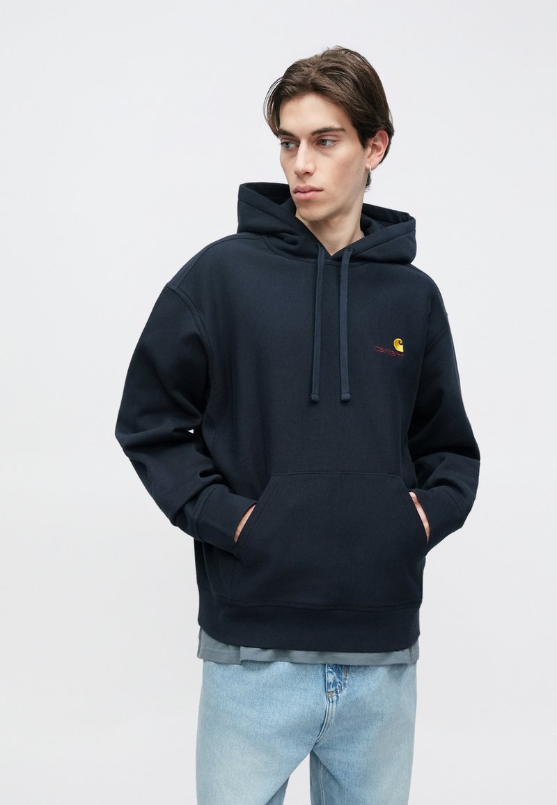 Marineblauwe hoodie van zachte stof, met een kangaroezak, een capuchon met trekkoord en een klein logo op de borst. Casual pasvorm en stijl.
