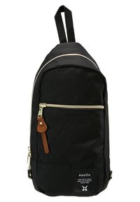 Zaino in tela nera con tasca anteriore con zip, dettagli color crema e un tirante in pelle. Dotato di una robusta maniglia superiore per il trasporto.