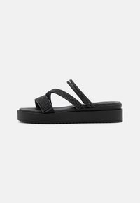 Sandales à plateforme noires avec des brides texturées, une semelle lisse et une semelle ergonomique. Comprend un design avec deux brides étroites et une bride large.