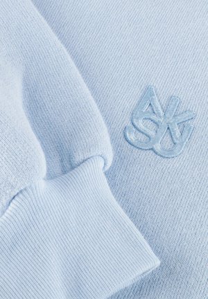 Lichtblauwe gebreide stof met geribde manchet en bijpassend geborduurd abstract logo op de zachte stof van het kledingstuk.