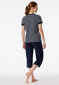 Marinblå randig t-shirt med korta ärmar och rund halsringning, tillsammans med marinblå cropped byxor. Tillverkad av bomull, avslappnad passform, minimalistisk design.