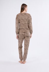 Dvoudílné pyžamo s leopardo vzorem v béžové barvě, které má dlouhé rukávy, elastické manžety a kalhoty s elastickým pasem.