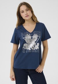 Maglietta in cotone blu navy con scollo a V, maniche corte e una grafica argentata di un'aquila con rose, insieme al testo "FOREVER STRONG."